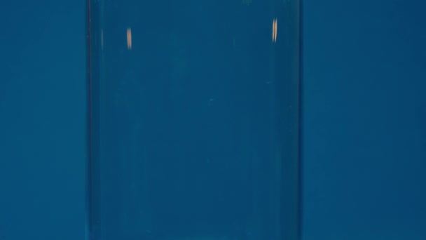 冰立方体的慢动作特写掉进一个空的透明玻璃杯里 背景蓝色 芭比娃娃的核心芭比酒 高质量的4K镜头 — 图库视频影像