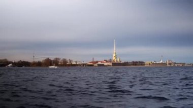Peter ve Paul Fortress St. Petersburg, Rusya 'da. Katedralin altın kulesi, güçlendirilmiş taş duvarlar, Rus donanmasının bayrağı. Güneşli bir günde Neva Nehri 'nin manzarası. Yüksek kalite 4k