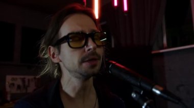 Müzik stüdyosu. Stüdyoda gitar çalıp şarkı söyleyen şık bir rock müzisyeni. Bir rock grubunun provası. Uzun saçlı ve gözlüklü bir adam. Sanatçı. Yüksek kalite 4k görüntü