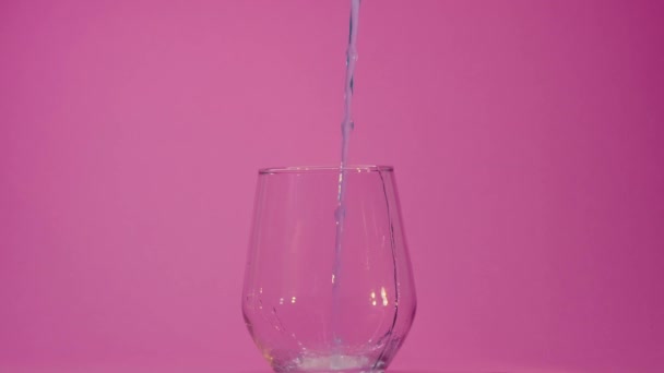 爽やかな炭酸飲料が透明なガラスに注ぎ込まれ 泡が見えます ピンクの背景 高品質の4K映像 — ストック動画