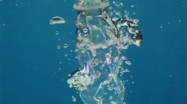 Plastik ve metal enkazının yavaş çekimde su altında alçalması hava kabarcıkları oluşturur. Filtrelenmemiş atık batar, küresel okyanus kirliliğini şiddetlendirir