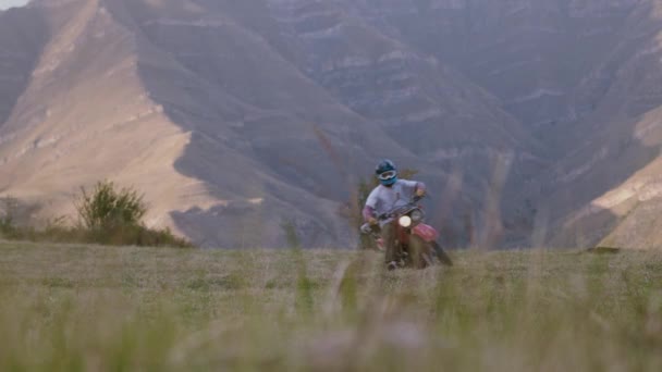 在雄伟的群山的背景下 一个男人骑着他的老式内蒙古摩托车踏上了令人振奋的旅程 带着无拘无束的自由精神 在开阔的田野中狂奔 吼叫着 — 图库视频影像