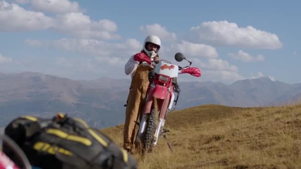 Мужчина Мотоциклист Снимает Свой Шлем Возле Винтажного Внедорожного Эндуро Мотоцикла — стоковое видео