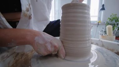 Seramik sanatçısı bir kız çömlekçi çarkında vazo yapıyor. Kadın sanatçılar yaratıyor, başarıyor, feminizm iş başında. Omzunun arkasından ellerle çalışmanın güzelliğine bak. Yavaşça yaklaş.