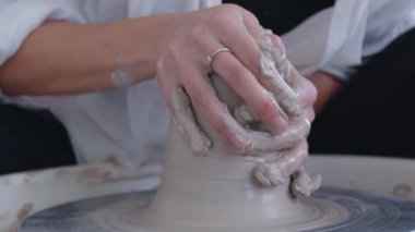 Seramik sanatçısı bir kız çömlekçi çarkında vazo yapıyor. Kadın sanatçılar yaratıyor, başarıyor, feminizm iş başında. Omzunun arkasından ellerle çalışmanın güzelliğine bak. Yavaşça yaklaş.