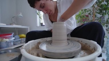 Genç ve yetenekli bir seramik sanatçısı, kilin kalıbını tutkulu bir şekilde çömlek çarkının üzerindeki kilden bir vazoya dönüştürüyor. Elleri, çamura batmış, ustalıkla sanatsal görüşünü getiriyor.