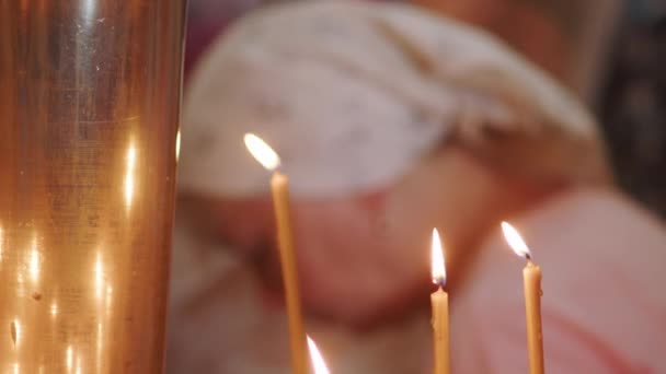 一个戴头巾的女人在神殿里的东正教教堂里向上帝祈祷 并在圣像前面放蜡烛 东正教教堂里正在燃着教堂的蜡烛 在东正教教堂点着蜡烛 — 图库视频影像