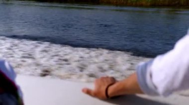 Bir adamın eli bir sürat teknesinin yatında dinleniyor. Dalgalar ve köpükler bırakarak hızla süzülüyorlar. Nehirde bir motorlu tekne gezisi. Zengin insanların geri kalanı. Beyaz gömlekli bir beyefendi seyahat ediyor.