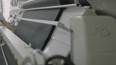 Tekstil fabrikası. Kumaş rulosunu döndürmek. Giysi üretimi için kumaş rulolarını kesme makinesi. Giysi fabrikası. Kumaş için modern makineler. Kumaşla çalışıyorum. Aşırı üretim krizi.