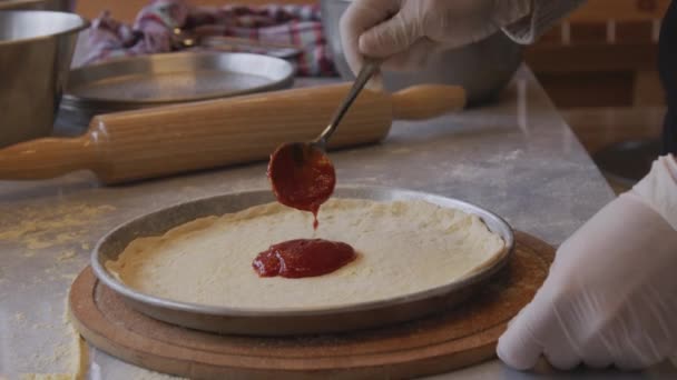 Mężczyzna Fartuchu Rozsypuje Pastę Pomidorową Podstawie Ciasta Pizzowego Stole Posypanym — Wideo stockowe