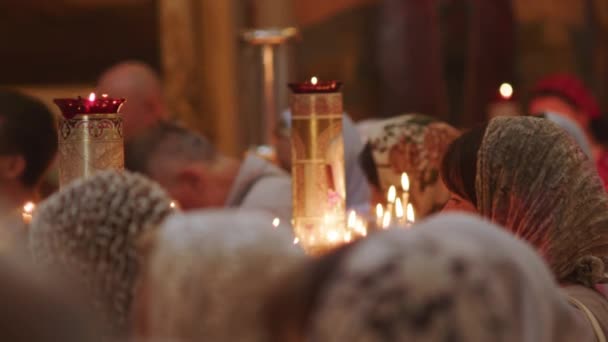キャンドルライトの暖かい光は ヘッドスカーフの崇拝者が崇拝する神聖な教会の内部を浴びます 焦点は 熟考中の女性 彼女の表情に囲まれている — ストック動画
