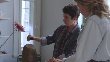 Bu çerçeve bir anne ve çocuğu yaklasik olarak 30 'lu ve 8 yaslarinda, ahşap bir masada çömlekçilikle mesgul olarak yaklasiyor. Sıradan bir kot gömlek giyen anne onu denetliyor.