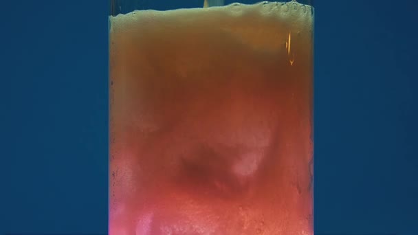 크리스탈 명확한 유리는 파란색 배경에 대하여 덩어리 복숭아 폭포로 음료의 — 비디오