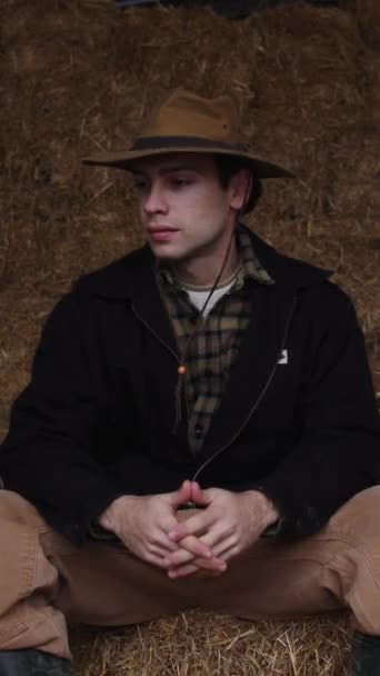 Ένας Νεαρός Αγρότης Κάθεται Σκεπτικά Έναν Αχυρώνα Περιτριγυρισμένος Από Δεμάτια — Αρχείο Βίντεο
