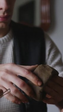 Bağımsız bir LGBT seramik sanatçısı kil şekillerini yetenekli ellerle şekillendirir, dikey 4K 'lık çekimle zanaatın samimiyetini vurgular. Odaklanmış ve yaratıcı, sanatçı rahat bir stüdyoda çalışıyor.