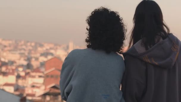 这幅画面捕捉了两个人在柔和的晨光下的一个柔嫩的瞬间 晨光沐浴在背景中的城市景观中 重点是两个朋友 一个是卷发的朋友 — 图库视频影像