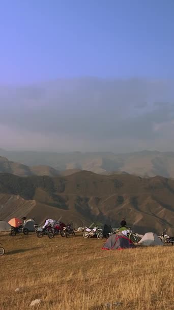 一个宁静的自行车手营地坐落在宏伟的山脉起伏的褶皱之间 帐篷和摩托车点缀了整个风景 在一天结束时为旅行者创造了一个临时的避难所 — 图库视频影像