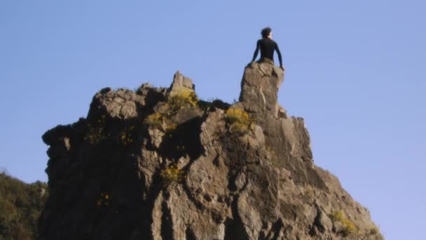 Ein Bergsteiger Steht Siegreich Auf Dem Schroffen Gipfel Die Arme — Stockvideo