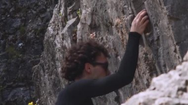 Bu yüksek çözünürlüklü 6K videosu, tırmanışın ortasında odaklanmış bir kaya tırmanıcısını yakalıyor ve sporun fiziksel taleplerine ayrıntılı bir bakış sağlıyor. Uzun kollu siyah bir atletizm bluzu giyen dağcı...