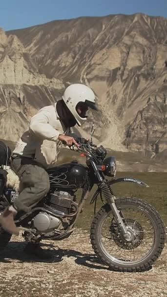 縦のProresショットは 速い出発前にバイクを蹴るので 予想の瞬間にオートバイをキャプチャします 冒険のための服装 ライダーは劇的に設定されています — ストック動画