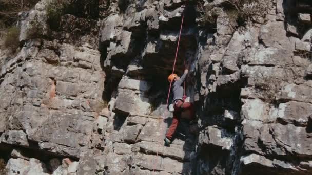 强壮的女登山者爬上陡峭的岩石山墙 女运动员克服了困难的路线 从事极端体育业余爱好的概念 高质量的4K镜头 — 图库视频影像