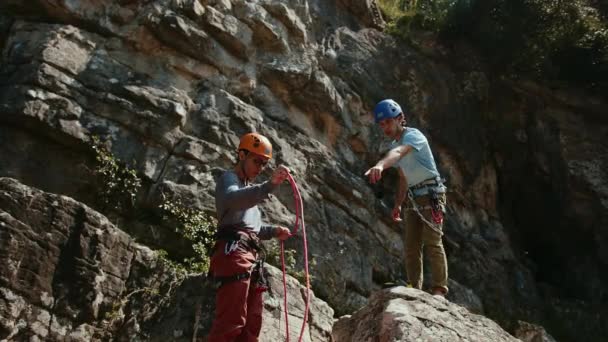 Dvojice Horolezců Porovnává Své Vybavení Drsným Skalním Pozadím Jsou Pozorní — Stock video