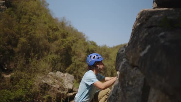 独木舟攀登者在蓝色中攀爬着陡峭的一面 有着浓密的意蕴和苍翠的大自然 高质量的4K镜头一个身穿蓝色头盔的孤身一人稳步爬上陡峭的悬崖 登山者 — 图库视频影像