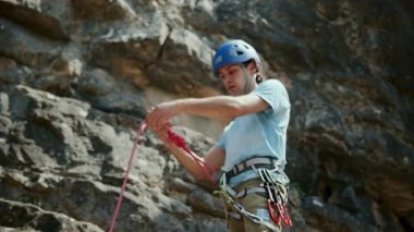 Dağcı adam halatı kontrol ederek kayalık duvar yarığına tırmanmaya hazırlanıyor. Aşırı aktif spor aktivitelerine tırmanıyorum. Aktif insanlar, açık hava aktiviteleri. İp detay çekimi. Düşük hareket 4K video. Yüksek