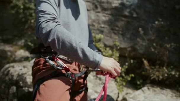 这张照片放大了一个攀岩者的中间部分 用手巧妙地盘绕着一根粉红色的攀岩绳 登山者的灰色衬衫和红色裤子在一定程度上是看得见的 同样可见的还有攀登者和攀登者 — 图库视频影像
