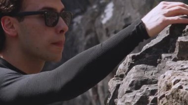 Bir dağcı, dikkatli bir hareketle, bu sinematik yavaş çekim videosunda dik bir kaya yüzeyinde yol alır. Geniş açı mercek, çevrenin büyüklüğünü ve dağcıların engebeli bölgelerle etkileşimini yakalar.