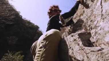 Bu 6K videosunda, tırmanışının bir sonraki aşaması için hazırlanan bir kaya tırmanışçısının odaklanmış ifadesi ve üst gövdesinin detaylı bir portresi yer alıyor. Tırmanışçıların yüzü kısmen görülebilir, gölgeli...