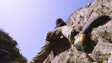 Bu 6K videosunda, tırmanışının bir sonraki aşaması için hazırlanan bir kaya tırmanışçısının odaklanmış ifadesi ve üst gövdesinin detaylı bir portresi yer alıyor. Tırmanışçıların yüzü kısmen görülebilir, gölgeli...