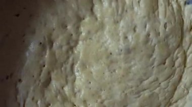 Mayanın mayalanma görüntüsü. Kabarcıklarla kaplı ve havadar bir dokusu var. Hamur yavaşça sallanırken yükselir ve çöker, doğal mayalanmayı gösterir.