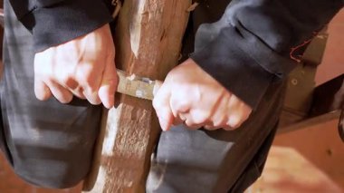 Eller ustalıkla ahşap bir kalasa karmaşık desenler oyuyor keskin bir keski kullanarak, ustalıkla ustalık göstererek. Kırsal atölye seti sıcak tonlarla, ahşap talaşlarıyla dolu.