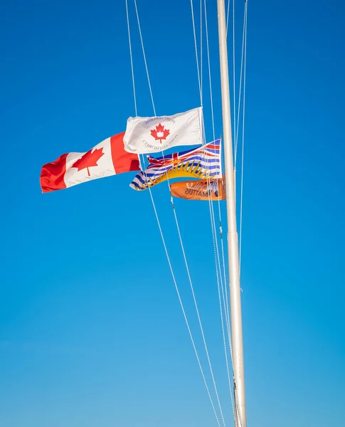 Canadian flag and British Columbia flag blowing in the wind. Travel photo, nobody, selective focus