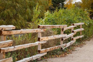 Kır Kereste Çiti. Arkasında yeşil bir tarla olan eski ahşap çitler. Ahşap çiftlik çitleri. Hiç kimse, sokak fotoğrafı, seçici odak