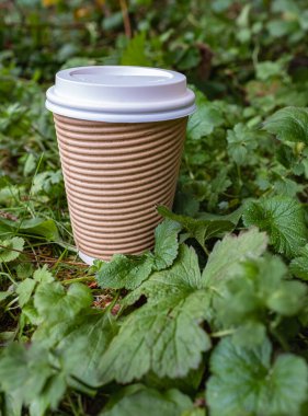 Yeşil yapraklı fincanlar için çevre dostu kahve. Geri dönüşümlü Kraft kağıt ambalajı ve sıfır atık konsepti. Kapaklı esmer kahve fincanı. Kahve ya da çay için kağıt bardak takımı.