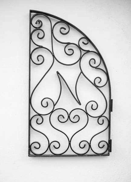 Decorative wrought iron hanging on the white wall. Wrought iron elements of decor. Nobody, street photo
