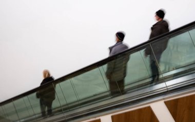 Yürüyen merdivenlerde koşuşturan insanlar. Hareket bulanıklığı. Alışveriş merkezinde yürüyen merdivende yürüyen insanlar. Bulanık, seçici odaklanma