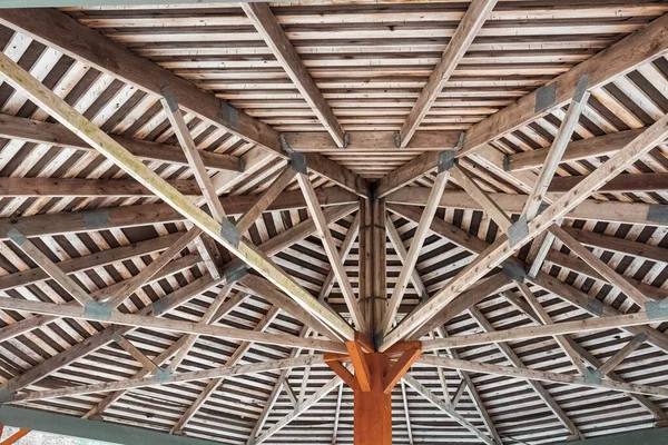 Part of the wooden roof structure on the gazebo. The inside roof of a wooden garden gazebo, looking up and out from within. Nobody, selective focus