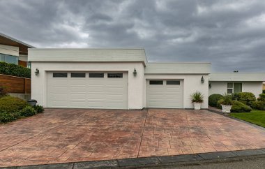 Residential house two car garage. Modern and luxurious double garage with driveway and roller door. Fragment of a luxury house with a garage door. Nobody, street photo clipart