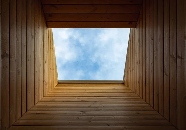Roof extension, roof window. Dormer window in a wooden sloping ceiling overlooking the blue sky. Sunlight enters the room through an attic window in wooden frame install. Mansard roof with skylight