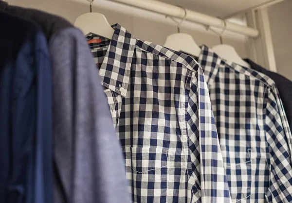 Mens wardrobe clothing hanging on rail in closet. Men\'s shirts hanging on a rack. Wardrobe clothing hanging on rail in closet. Nobody, selective focus
