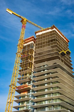 Building site with cranes new development in the city. Concrete high rise residential building under construction. Big high crain under a new construction site of high-rise building. Nobody, copyspace