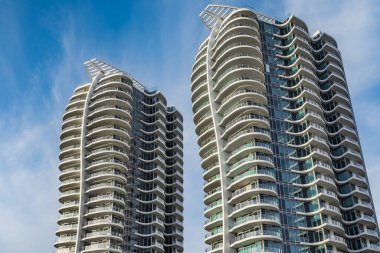 A highrise building against the blue sky. Condominium or apartment building. Looking Up Blue Modern Building. Architecture details Modern Building Glass facade-Surrey Canada-January 10,2023