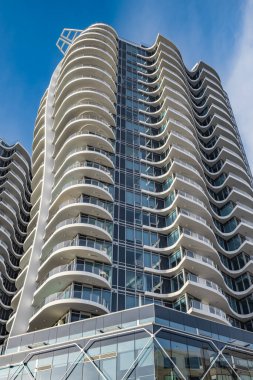 A highrise building against the blue sky. Condominium or apartment building. Looking Up Blue Modern Building. Architecture details Modern Building Glass facade-Surrey Canada-January 10,2023