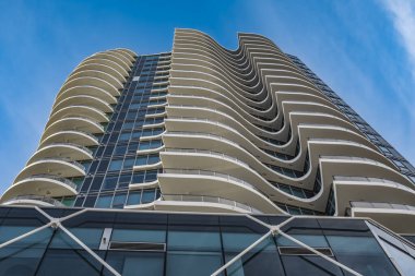 A highrise building against the blue sky. Condominium or apartment building. Looking Up Blue Modern Building. Architecture details Modern Building Glass facade-Surrey Canada-January 10,2023
