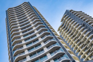 A highrise building against the blue sky. Condominium or apartment building. Looking Up Blue Modern Building. Architecture details Modern Building Glass facade-Surrey Canada-January 10,2023