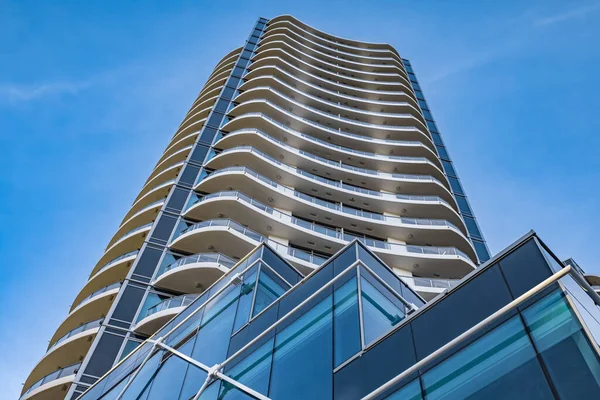 A highrise building against the blue sky. Condominium or apartment building. Looking Up Blue Modern Building. Architecture details Modern Building Glass facade-Surrey Canada-January 10,2023