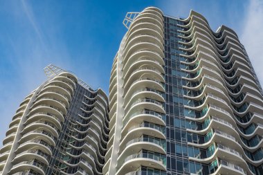 A highrise building against the blue sky. Condominium or apartment building. Looking Up Blue Modern Building. Architecture details Modern Building Glass facade-Surrey Canada-January 10,2023